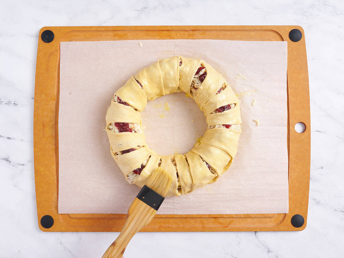 Brushing an egg wash over the wreath.