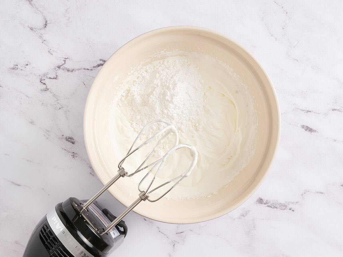 Whipped cream in a bowl with a handmixer.