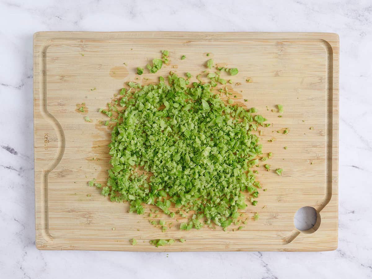 Diced broccoli on a wooden cutting board.