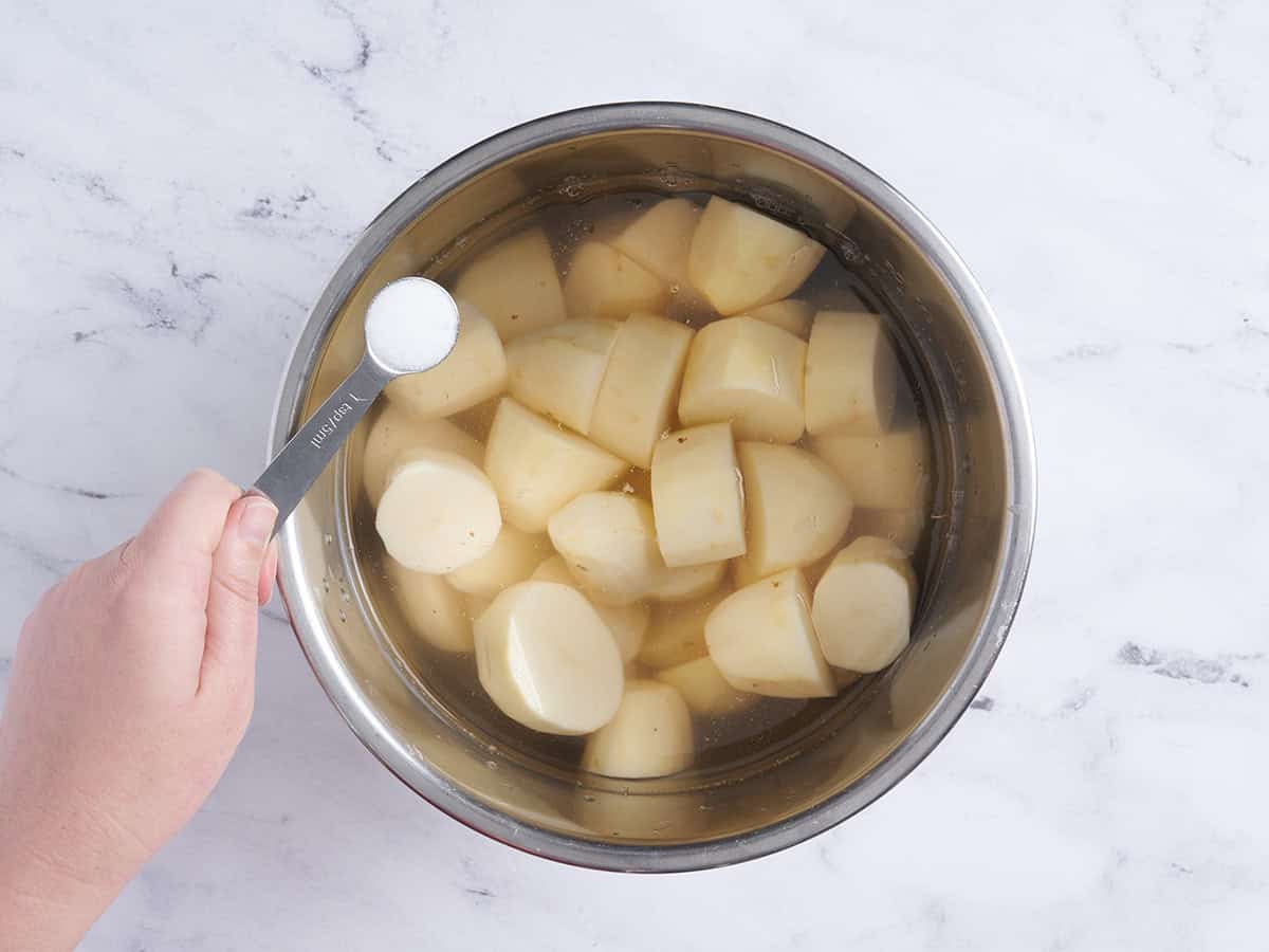 Diced potatoes and water in an instant pot with some salt about to be added.
