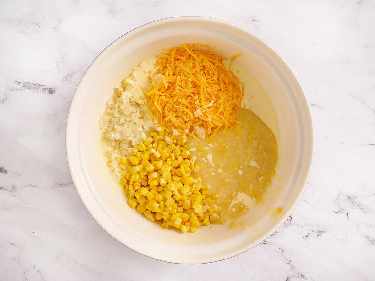 Adding canned corn, cheese, and onion to the yogurt/eggs bowl.