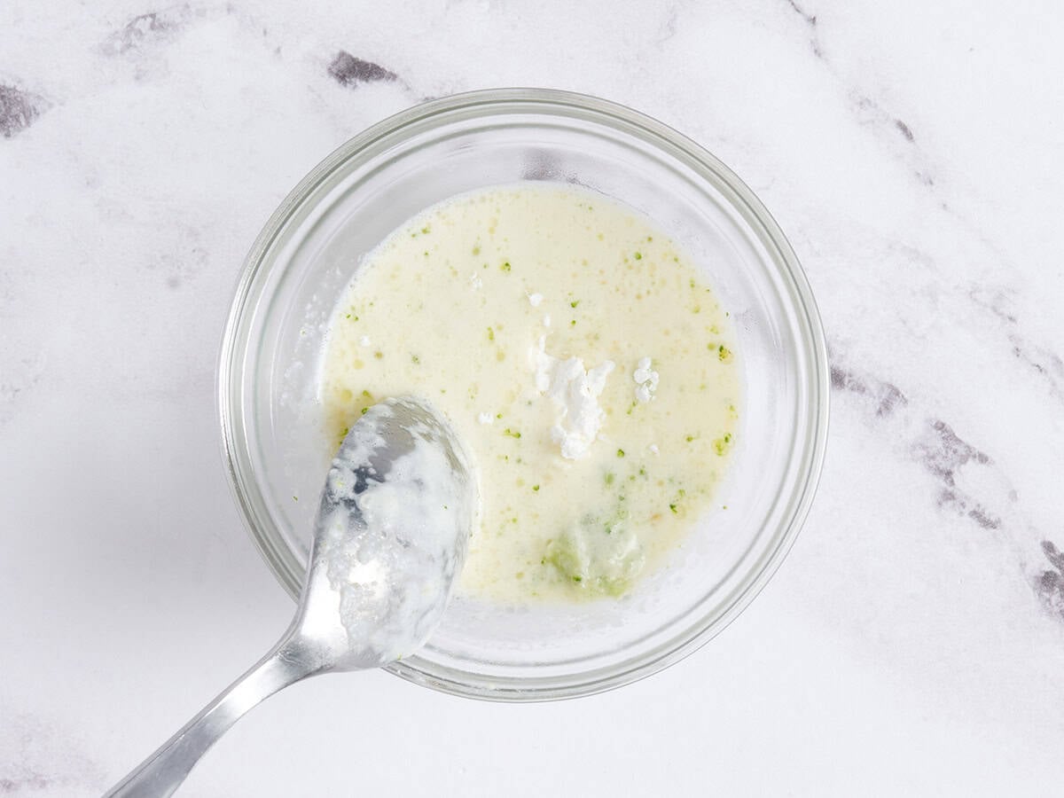 Milk and cornstarch in a bowl being mixed with a spoon.