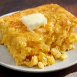 Cornbread casserole on a white plate with a pat of melting butter.