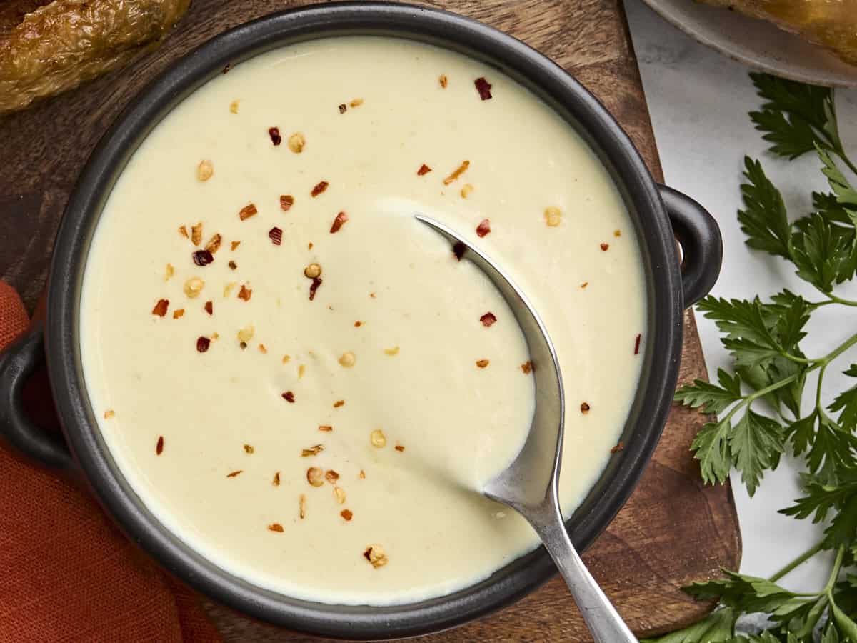 Overhead view of a bowl of cream of chicken soup with a spoon.