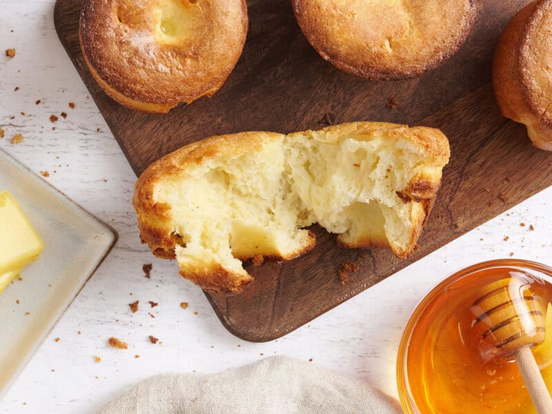 Popover ripped open on a cutting board with a bowl of honey