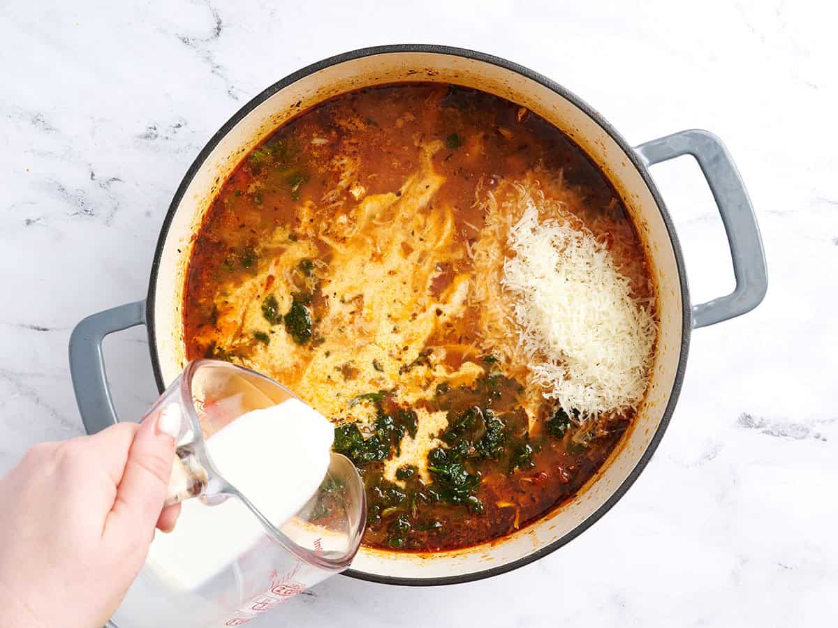 Pouring cream into the pot with Parmesan and spinach already added.