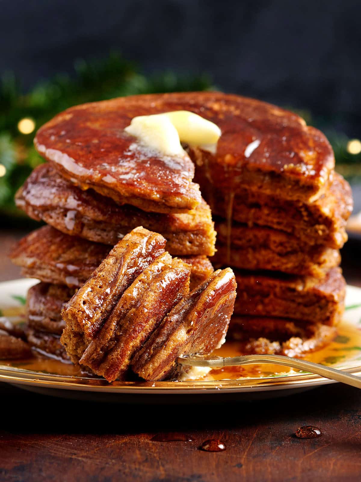 gingerbread pancakes stacked with butter on top and a fork biting into the stack