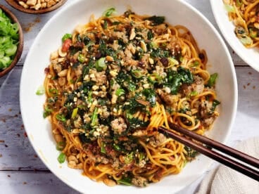 Overhead view of a bowl of dan dan noodles with chopsticks.
