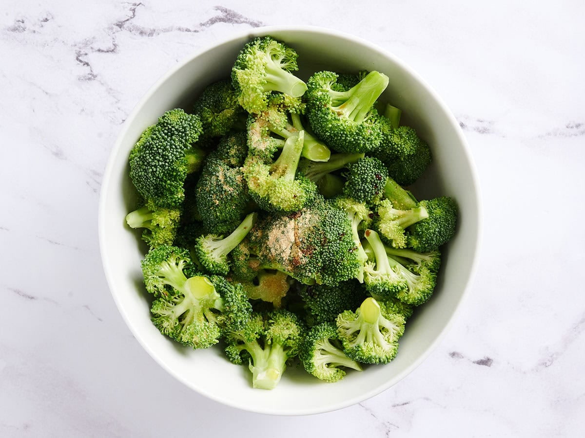Broccoli florets and seasonings in a bowl.