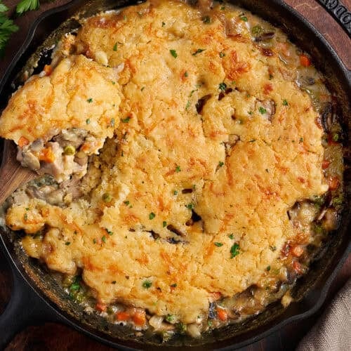 Overhead view of a homemade chicken cobbler with a spoon taking some.