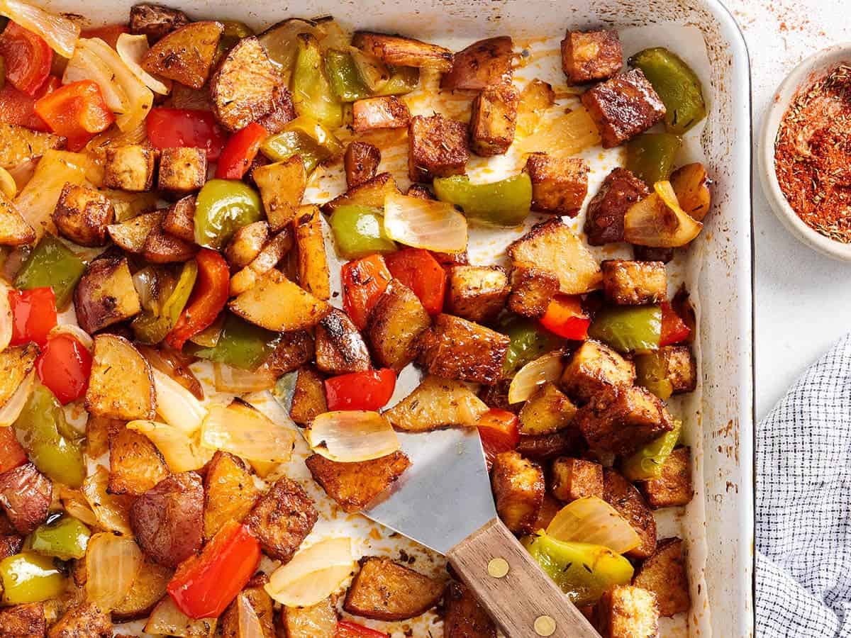 Sheet pan Cajun tofu and vegetables on a baking sheet with a spatula.