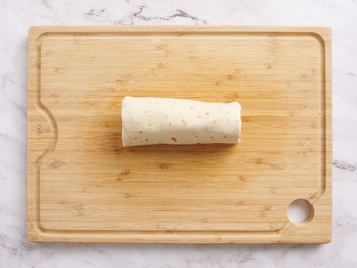 A rolled tuna wrap on a wooden cutting board.