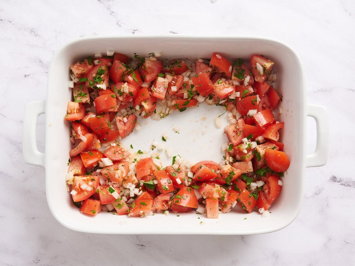 Diced tomatoes and onions in a baking dish.