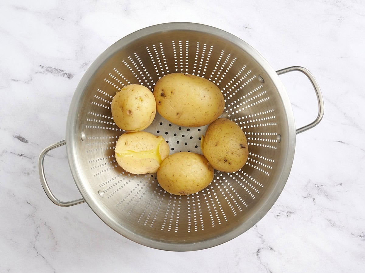 Whole boiled potatoes in a colander.