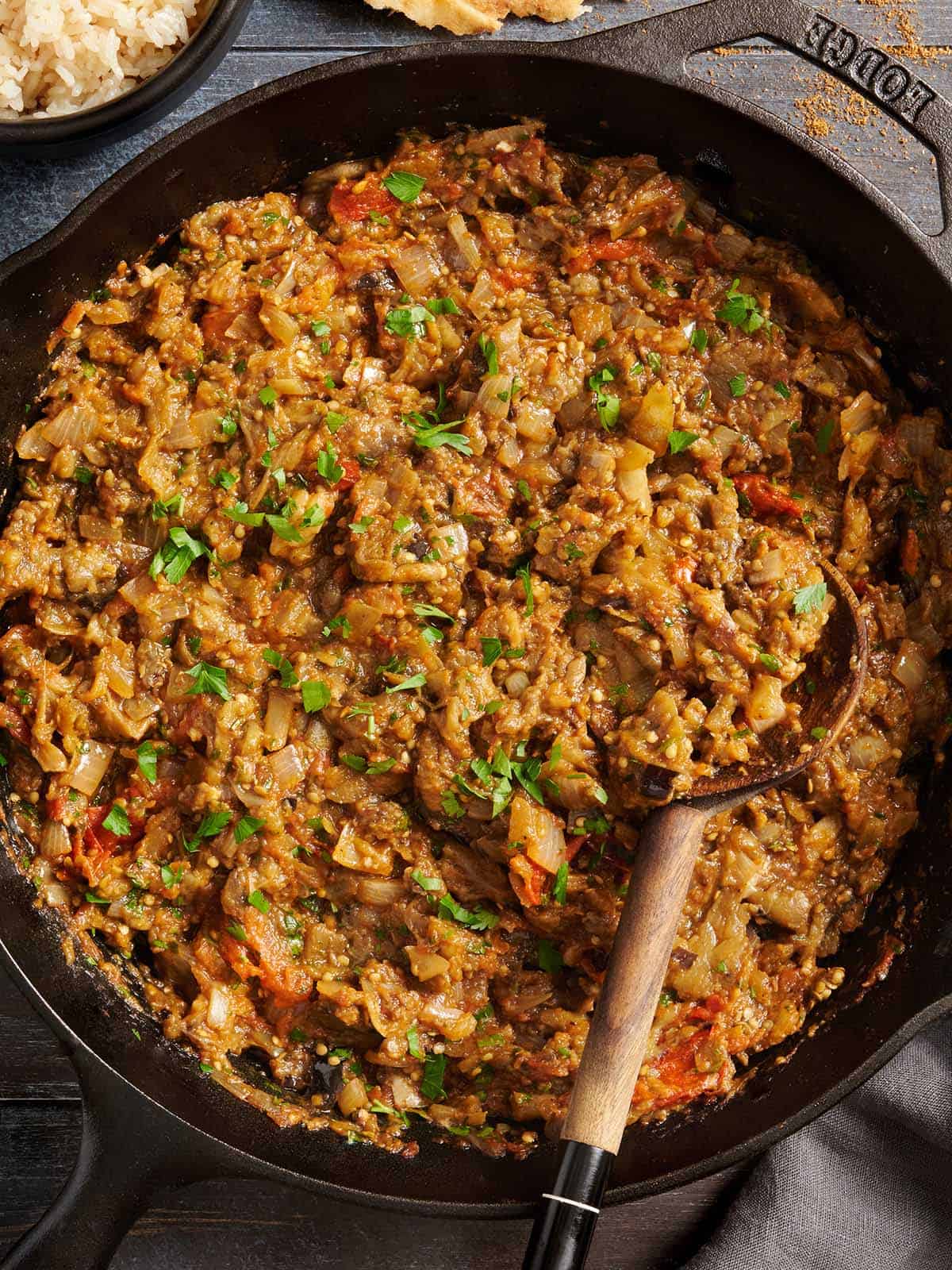 eggplant curry in a skillet with a spoon scooping some up
