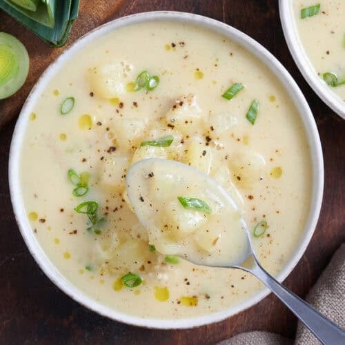 Overhead view of potato leek soup in a bowl with a spoon.