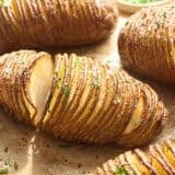Side view of hasselback potatoes on parchment paper.