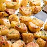 Oven roasted potatoes on a baking sheet with a spatula.