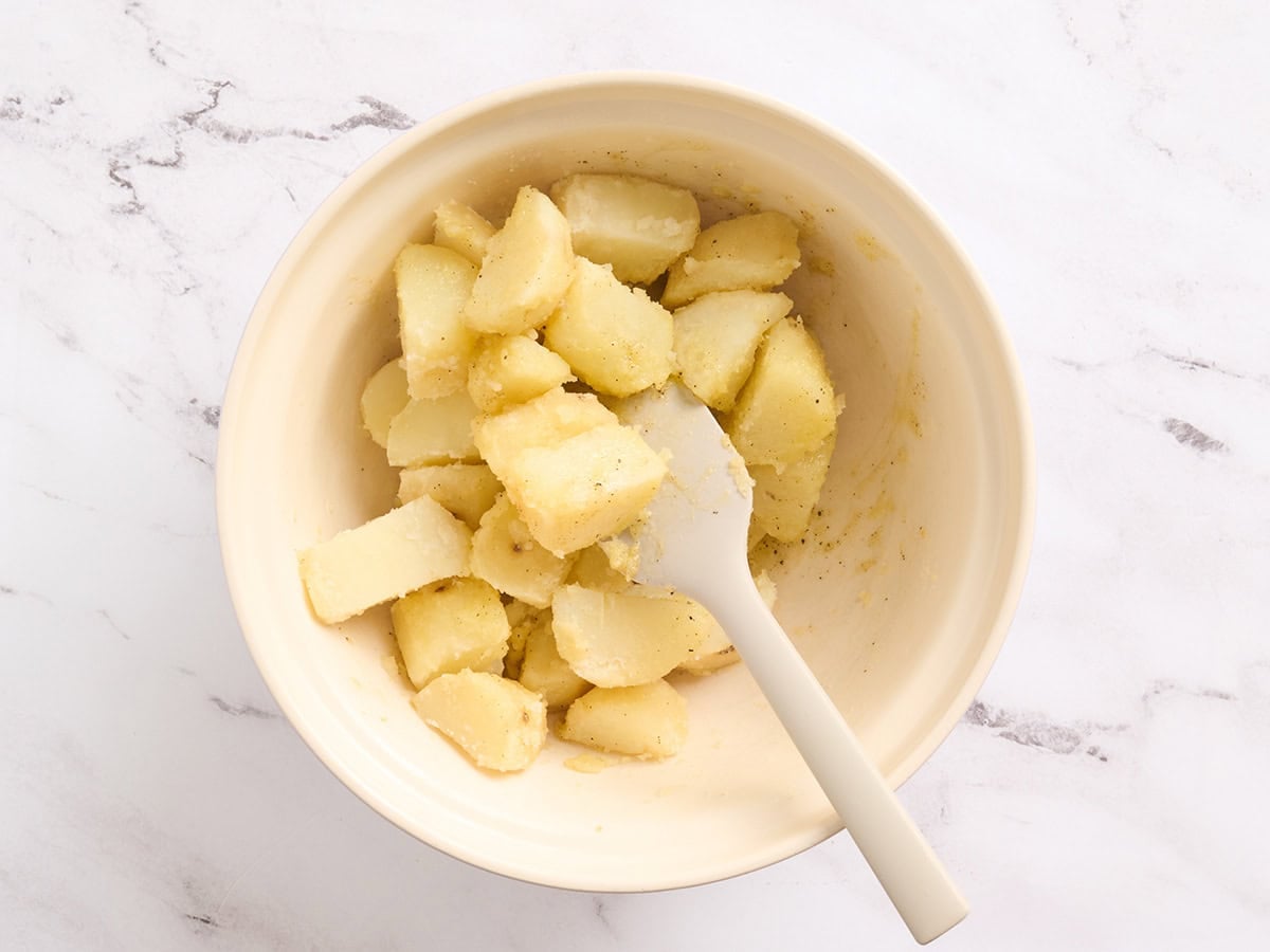 Potatoes being gently tossed with oil and seasonings.