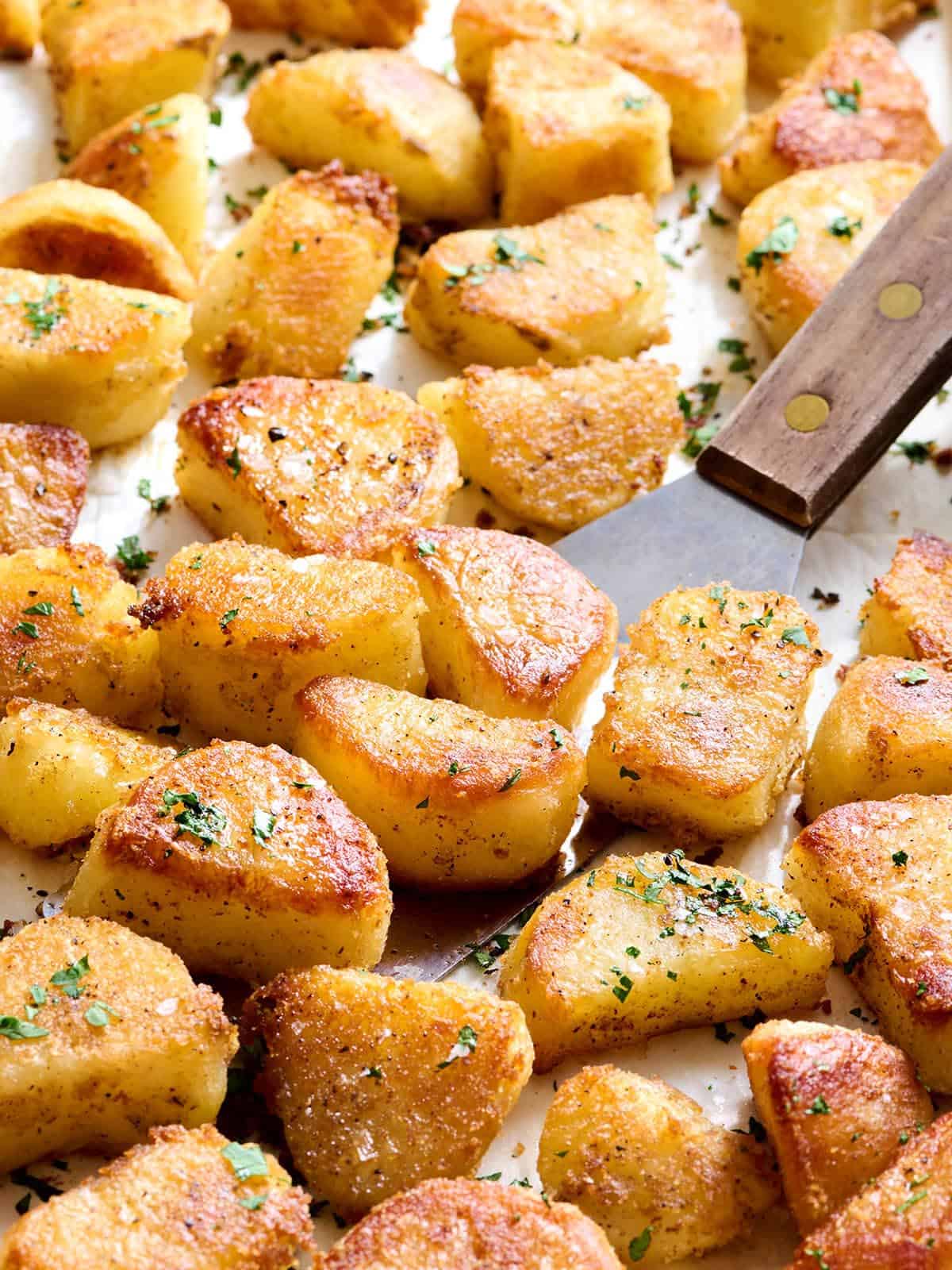 Oven roasted potatoes on a baking sheet with a spatula.