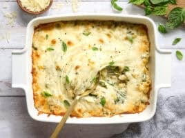 Overhead view of a casserole dish of baked pasta with spring veggies and a spoon.