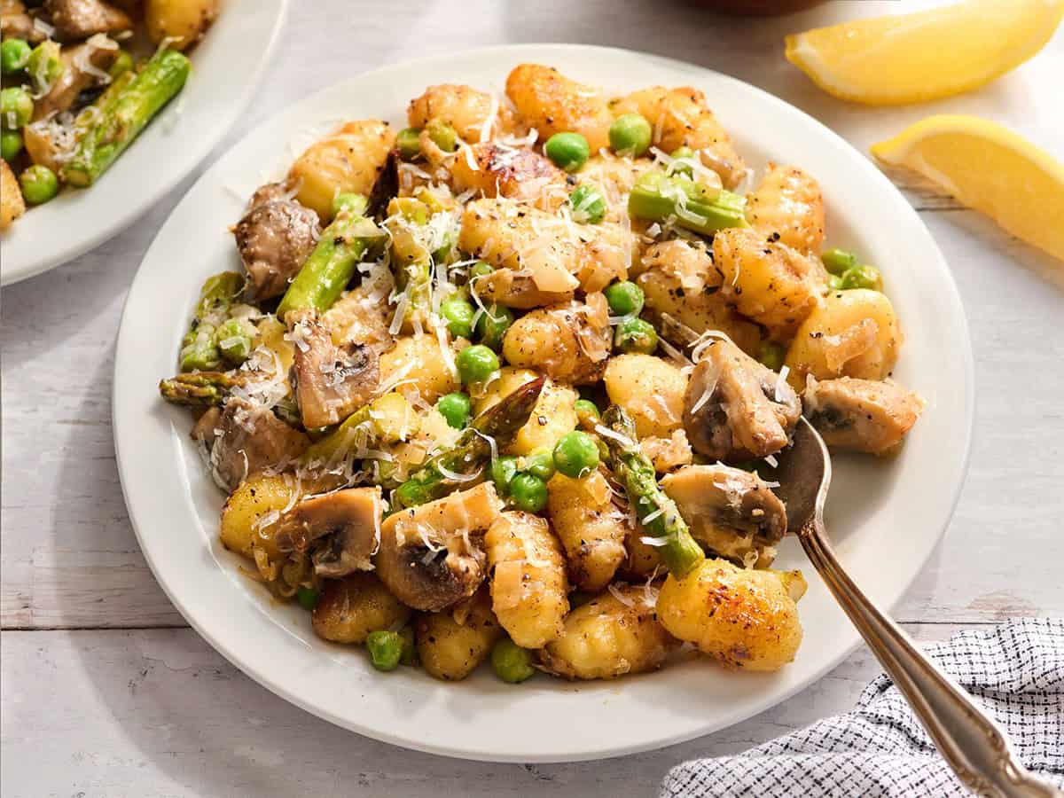 A plate of spring vegetable gnocchi on a plate with a fork.