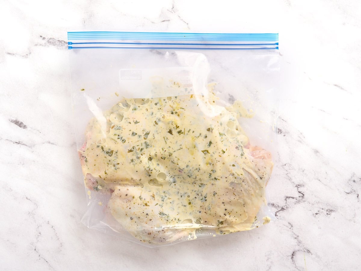 Chicken thighs in a ziptop bag marinating in a chimichurri marinade.