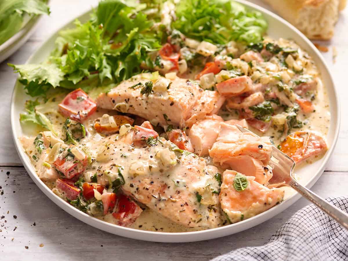 Side view of Tuscan salmon on a plate with salad.