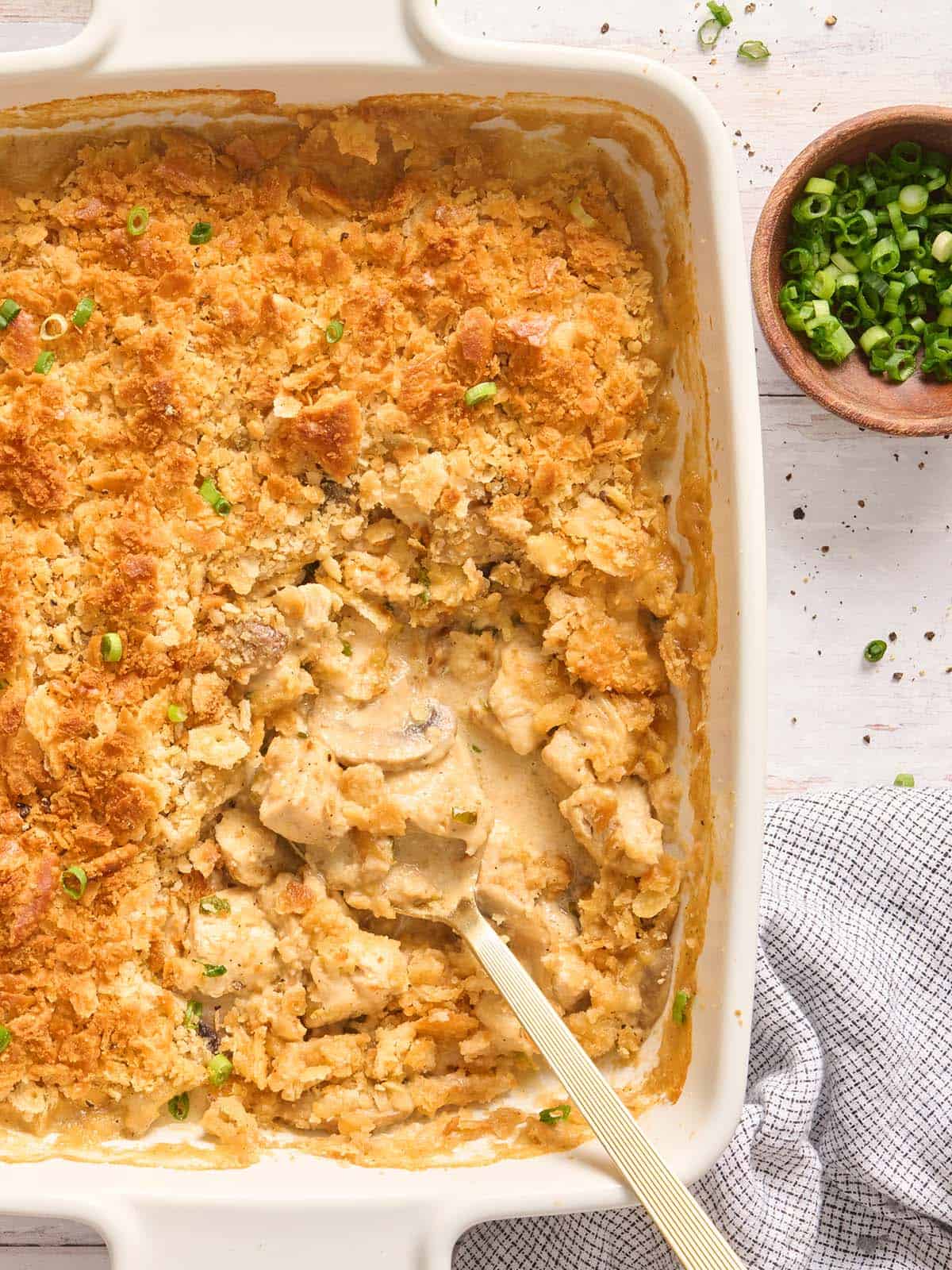 Overhead view of a million dollar chicken casserole in a casserole dish with a spoon.