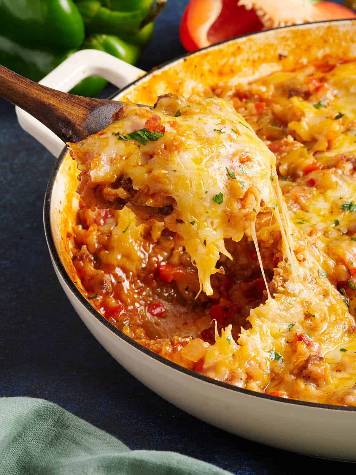 Side view of a spoon taking stuffed pepper skillet from a skillet.