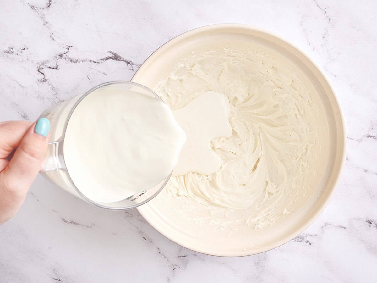 Cream being poured into whipped cream cheese.