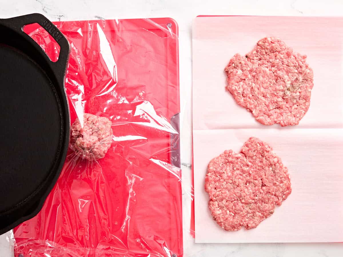 Ground beef being smashed with a skillet.