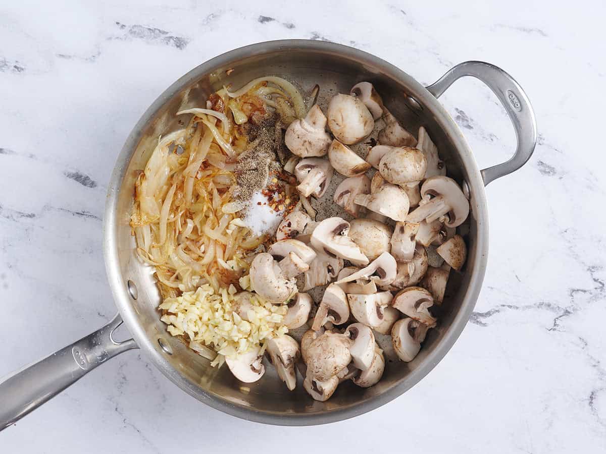 Garlic, mushrooms, caramelized onions and seasonings in a skillet.