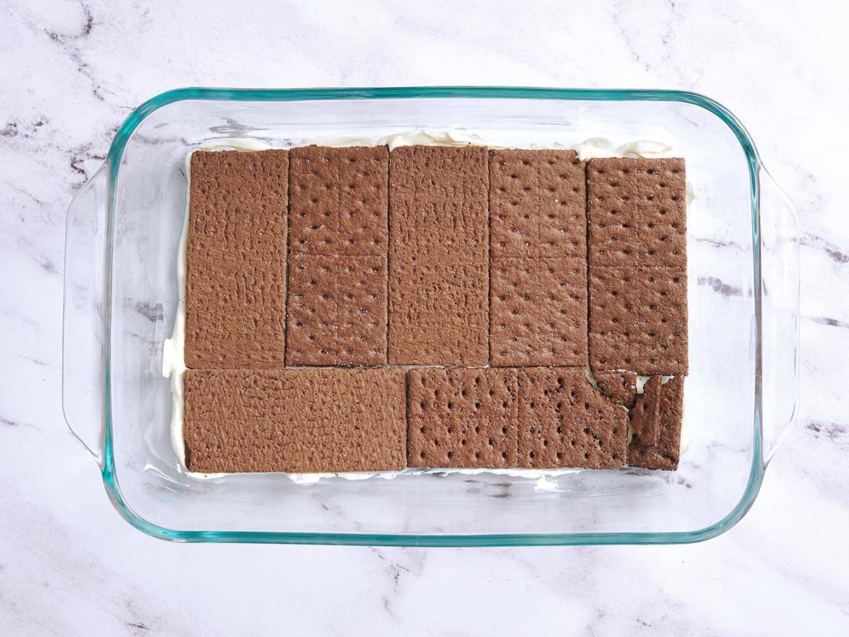 A layer of chocolate graham crackers added to a baking dish.