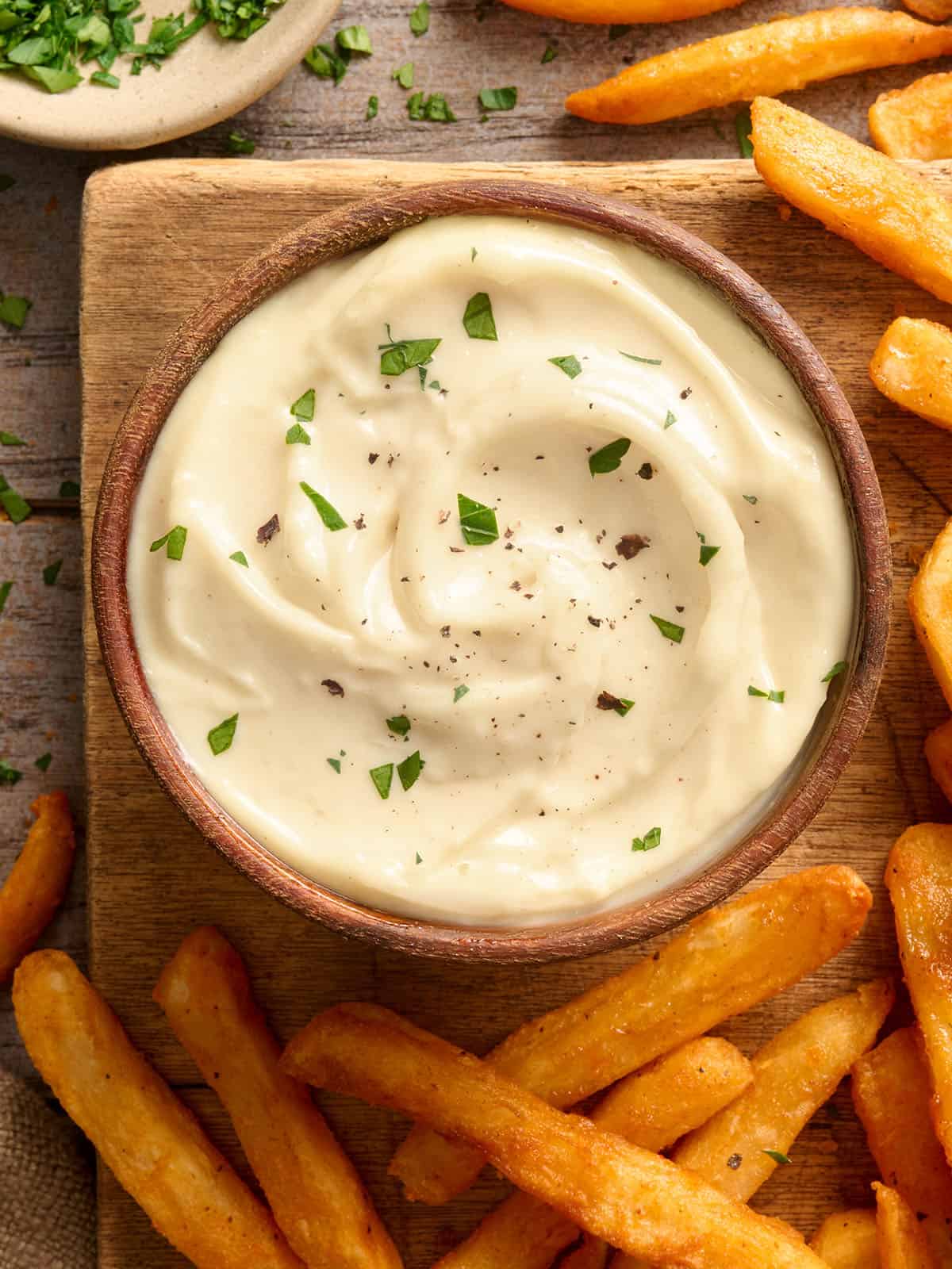 Overhead view of a bowl of homemade garlic aioli with fries.
