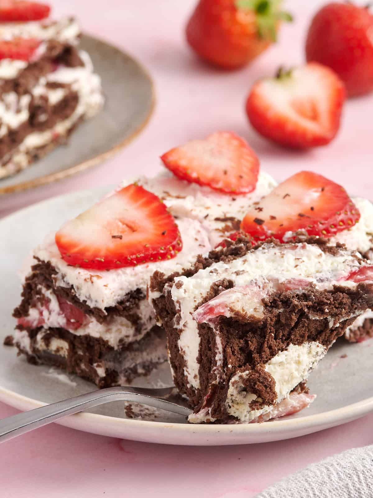 Side view of a slice of chocolate strawberry icebox cake with a fork taking some.