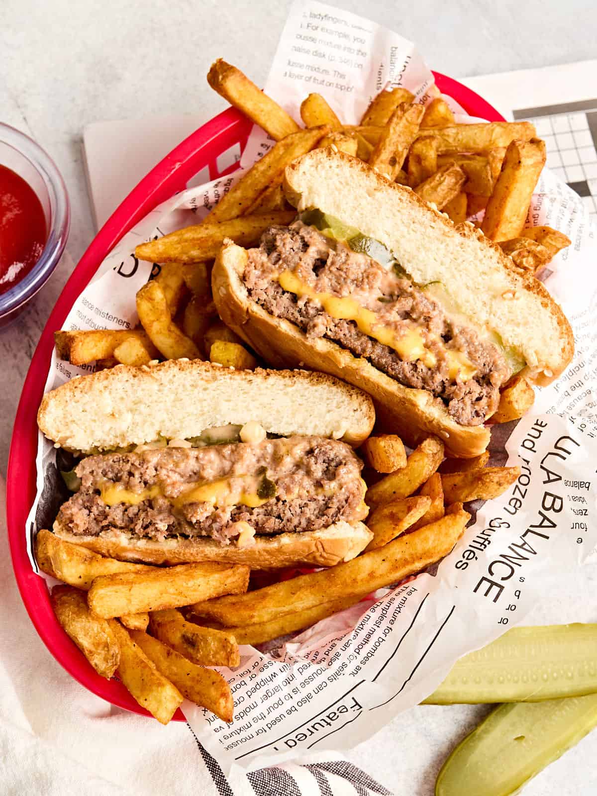 Overhead view of a cheese stuffed juicy lucy burger in a basket with fries.