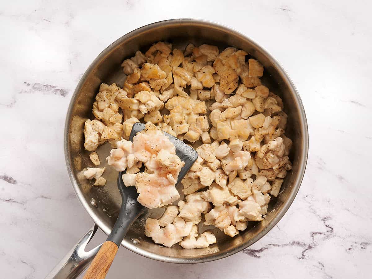 Diced chicken in a skillet being browned.