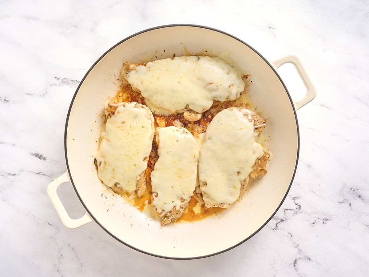 Chicken culets topped with melted mozzarella in a skillet.