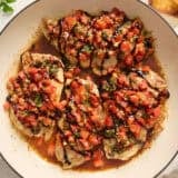 Overhead view of bruschetta chicken in a skillet topped with balsamic glaze.