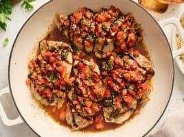 Overhead view of bruschetta chicken in a skillet topped with balsamic glaze.