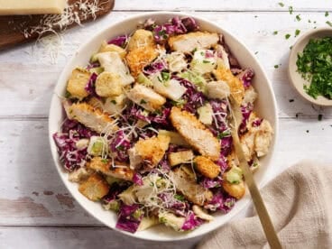 Overhead view of Casesar slaw with crispy chicken in a bowl with a fork.