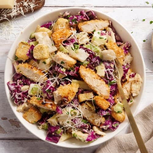 Overhead view of Casesar slaw with crispy chicken in a bowl with a fork.