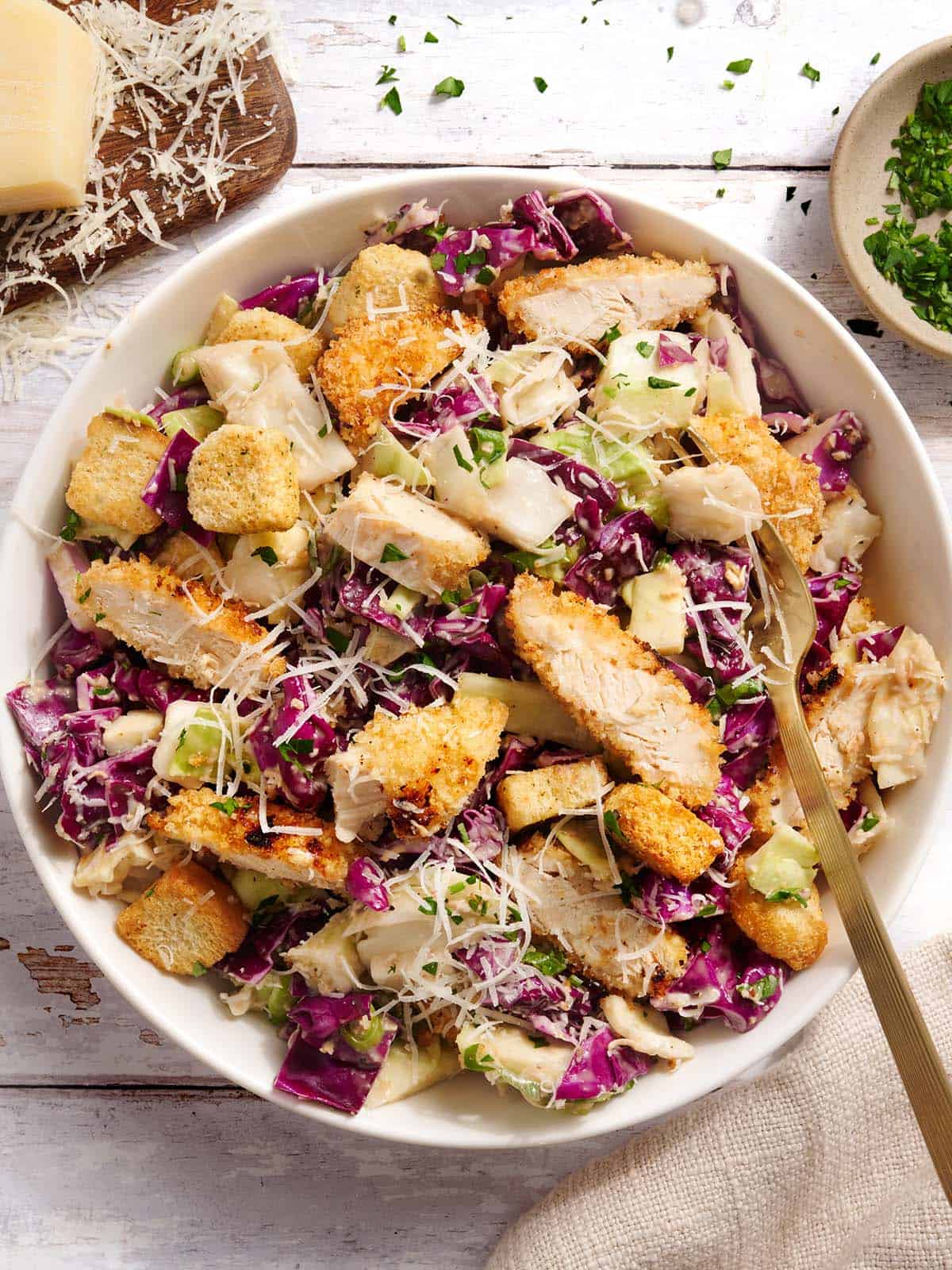 Overhead view of Casesar slaw with crispy chicken in a bowl with a fork.